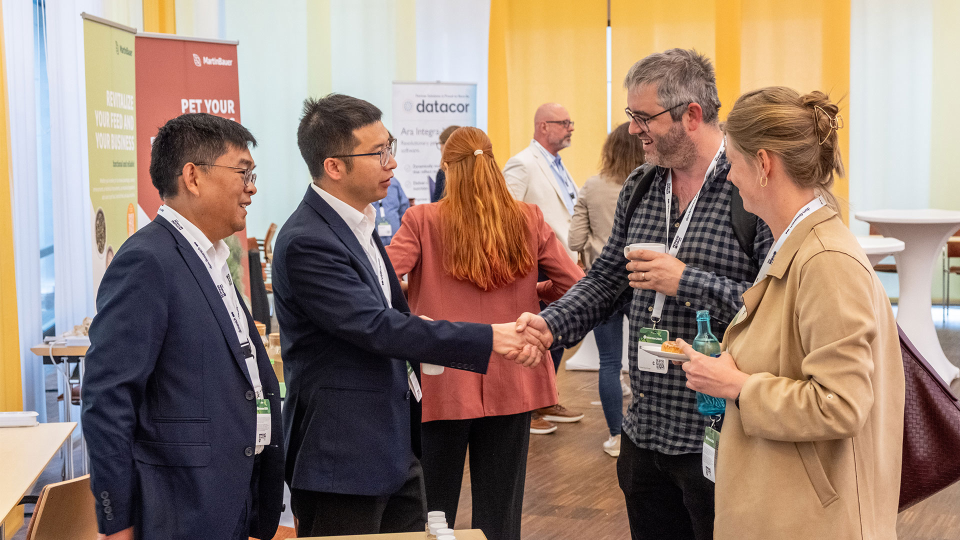 Two men shake hands with two other colleagues at Petfood Forum Europe
