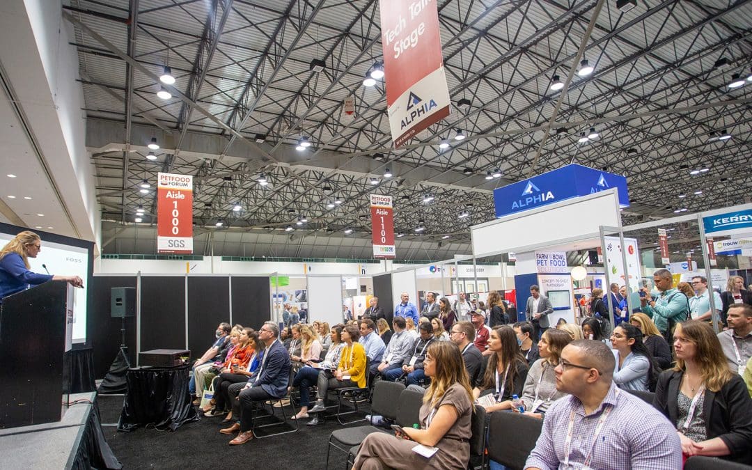 Women on stage speaking to a large crowd