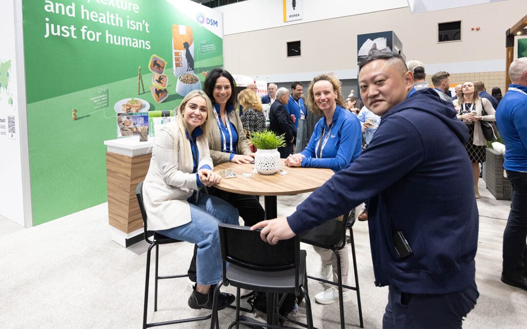 DSM booth staff smiling around a table at Petfood Forum
