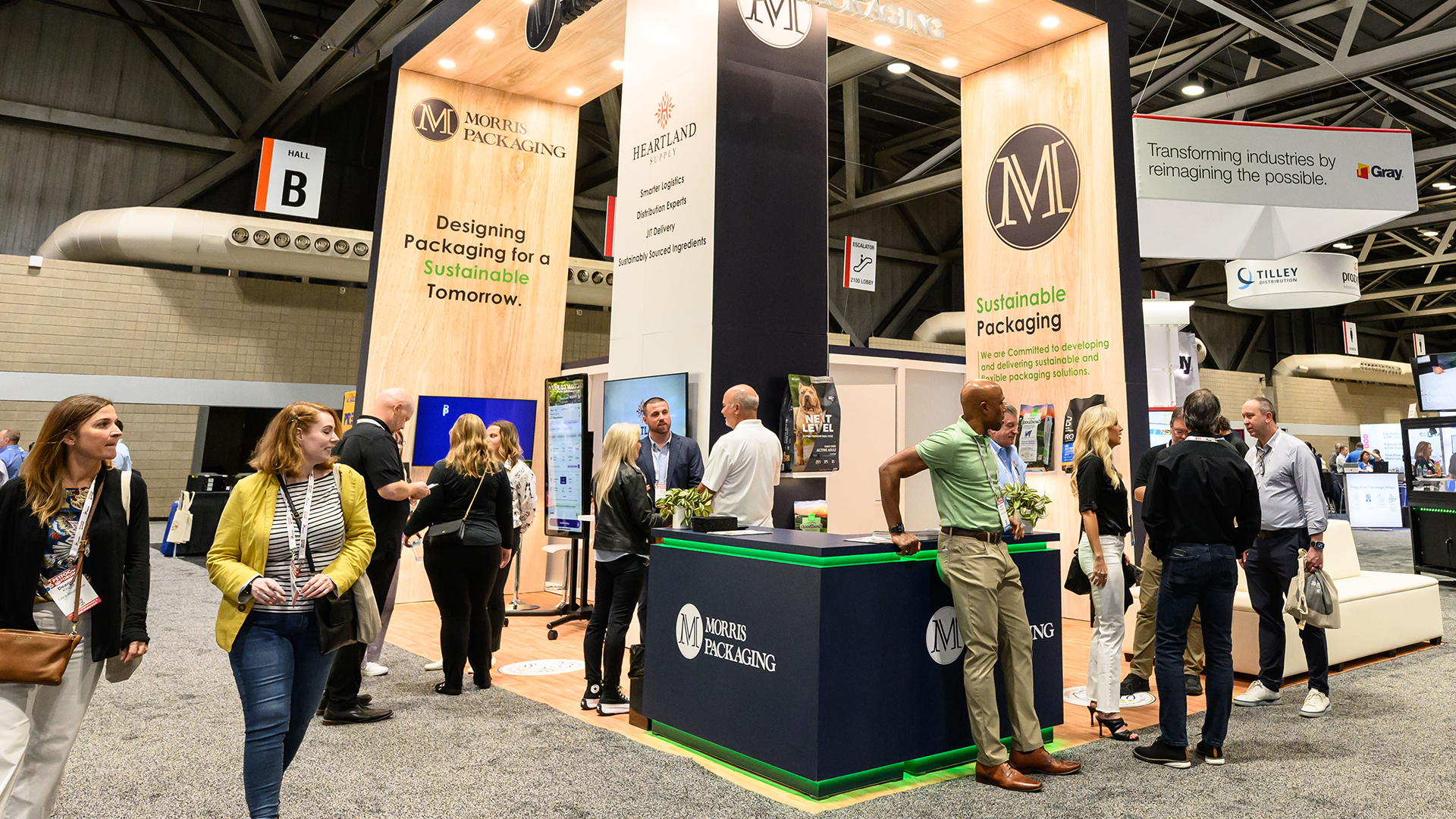 Crowd gathers at busy booth as people walk by at Petfood Forum